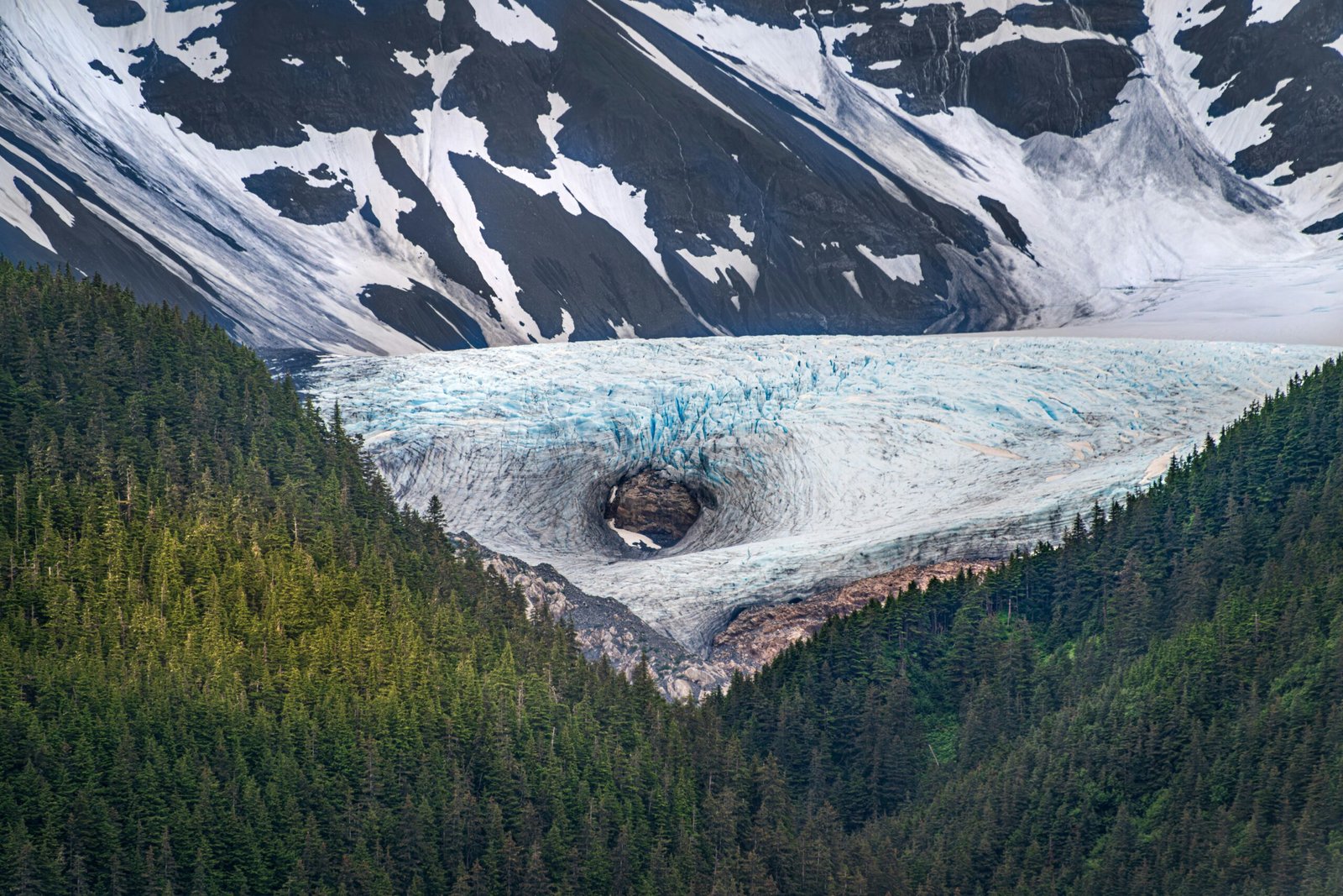 A large glacier surrounded by mountains and trees